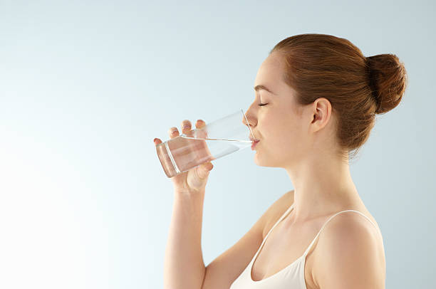 Jeune femme qui boit un verre d'eau filtrée