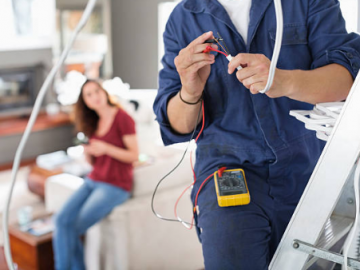 homme en combinaison de travail avec outil d'électricité et femme assise en arrière plan