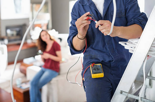 homme en combinaison de travail avec outil d'électricité et femme assise en arrière plan