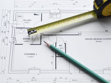 Plan d'un bien immobilier sur lequels sont posés un mètre et un crayon papier