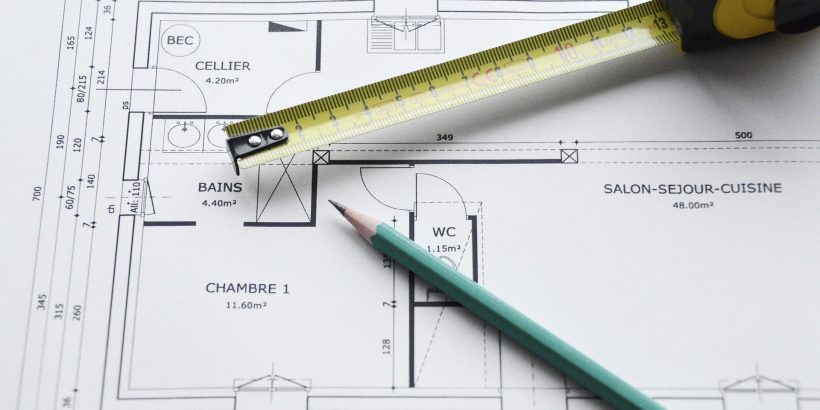Plan d'un bien immobilier sur lequels sont posés un mètre et un crayon papier