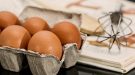 oeufs, fouet et livre de recettes posés sur une table